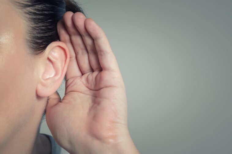 Close-up of a person holding their hand to their ear.