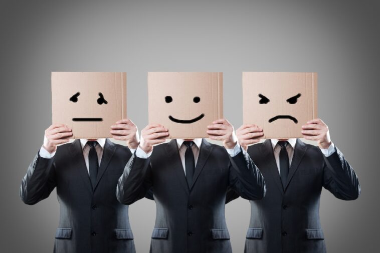 Three people in suits hold cardboard boxes with different emotional faces drawn on them.