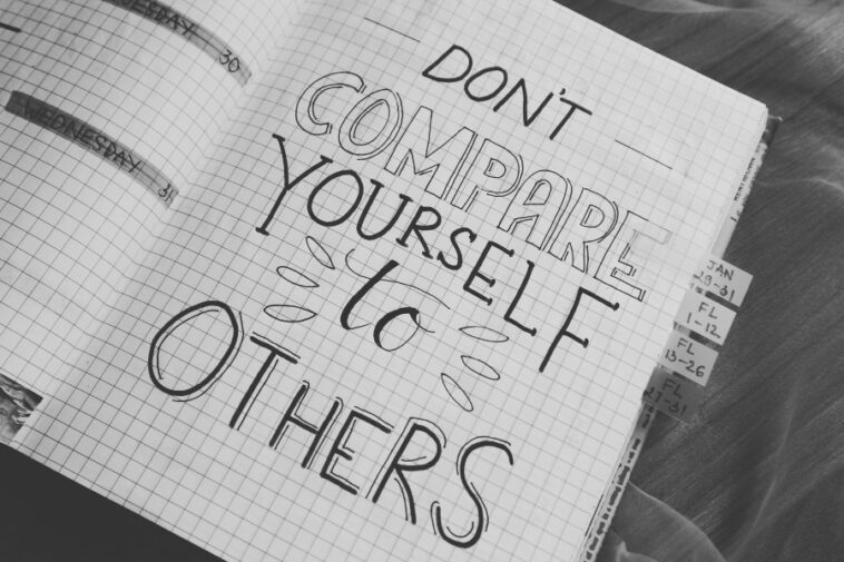 Open notebook with graph paper, handwritten message "Don't compare yourself to others," and date tabs.