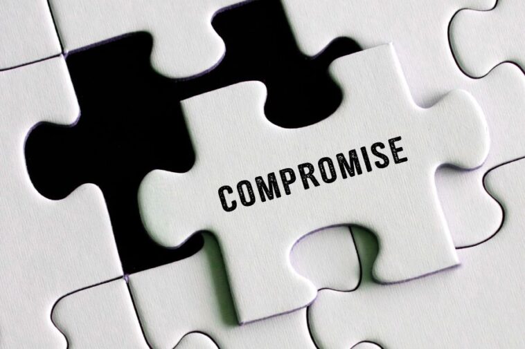Close-up of a white jigsaw puzzle with one piece slightly raised, bearing the word "COMPROMISE" in black text.