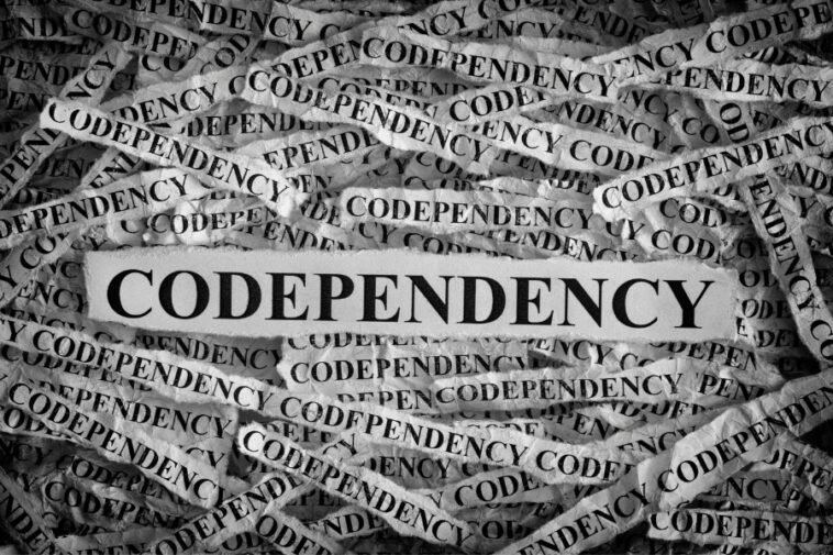Black and white image of torn paper strips, many reading "Codependency," surrounding a central strip with the same word in bold, black letters.