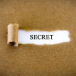 Brown paper with a torn opening revealing the word "SECRET" in black font on a white background.