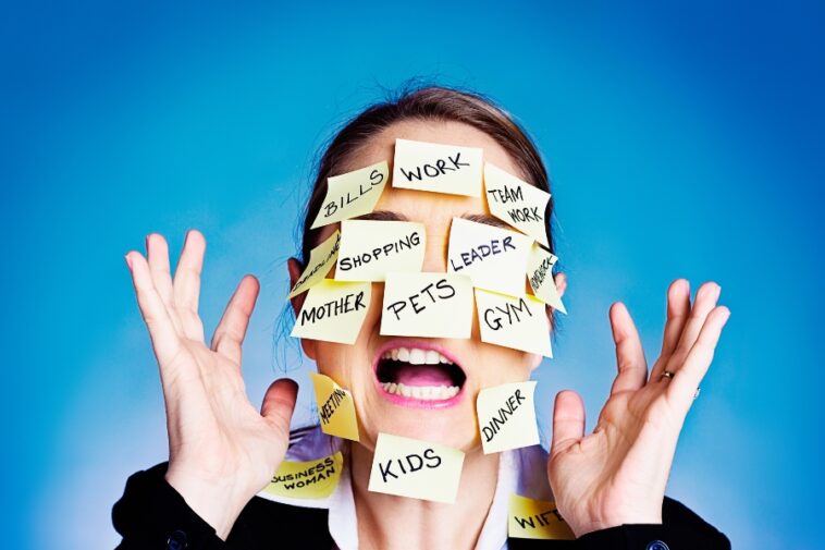 Woman with open mouth and hands raised, face covered in sticky notes with words like "Work," "Kids," and "Bills.