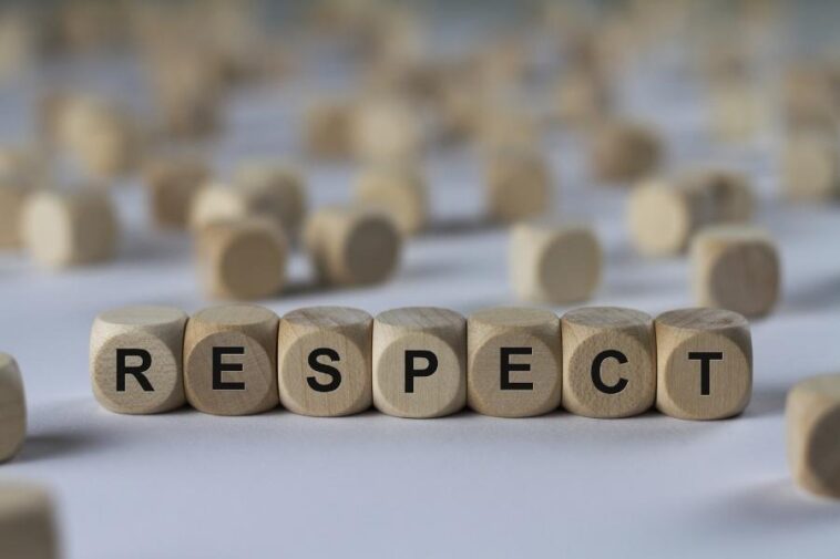 Wooden blocks spell out "RESPECT" in a line, with more blurred blocks scattered in the background.