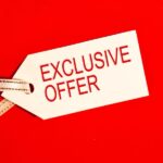 A white tag with "EXCLUSIVE OFFER" in red text attached with a gold-trimmed ribbon on a red background.