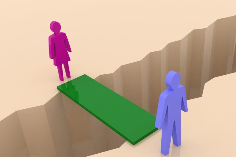 A pink figure stands on one side of a chasm, connected to a blue figure on the opposite side by a green bridge.