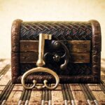 A decorative wooden chest sits on a bamboo mat, with a golden key resting against the chest's latch.