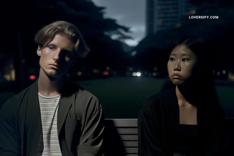 Moody image of a young Caucasian man and a young Asian woman seated separately on a park bench at dusk. The park is dimly lit, emphasizing their isolation and reflection. They are dressed in modern, stylish outfits, their expressions filled with deep thought and a subtle sadness, capturing the emotional gravity of a respectful breakup.