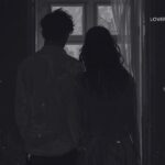 Silhouetted couple with shoulders touching, looking out a window at trees.