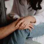 Close-up on a couple's hands, one wearing an engagement ring, gently touching.
