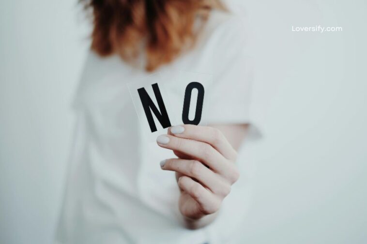 A person holds two clear cards with the black letters "N" and "O" on them, forming the word "NO".