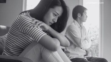 A woman in a striped shirt and jeans sits with her arms crossed and head bowed, while a man in a collared shirt and jeans sits with his arms crossed, both facing away from each other and looking out a window.